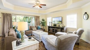 Ein Wohnzimmer mit Deckenventilator, Fernseher und einer Wanduhr.