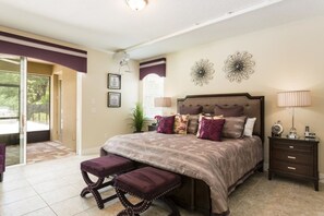 Un dormitorio con una cama grande, una mesita de noche, un banco y vistas al exterior.