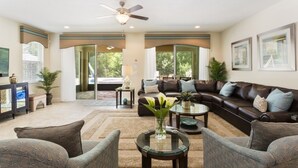 A spacious living room with a dark leather sofa, a glass coffee table, and a ceiling fan. - Je62429 - Reunion Resort - 8 Bed 8 Baths Villa (Kissimmee)