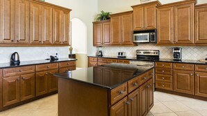 A kitchen with wooden cabinets, a central island, a microwave, a toaster, and a coffee maker.