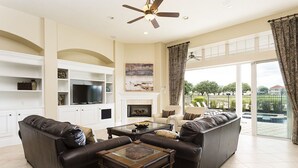 A spacious living room with a fireplace, a large TV, and a view of the outdoors.