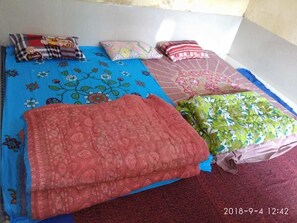 A bed with multiple pillows and a blanket. - Bhajan Ashram Neelkanth (Yamkeshwar)