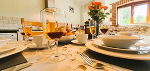 A dining table set with plates, bowls, glasses, and cutlery. - The Victorian Barn self catering holidays with pool & hot tubs (Blandford Forum)