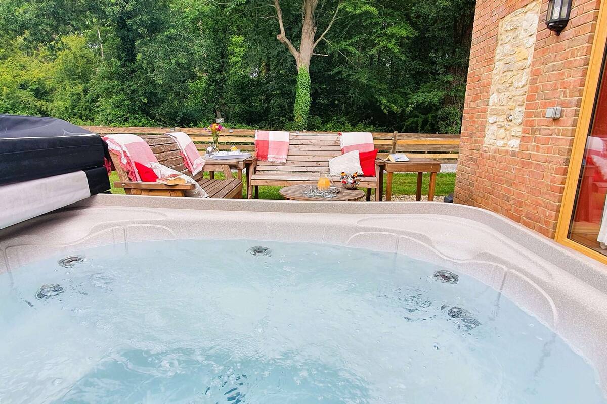 A hot tub with a wooden deck and outdoor seating area.