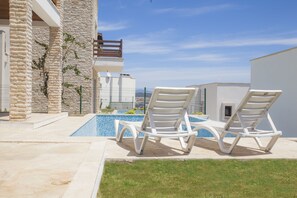 Una piscina al aire libre de temporada, sillones reclinables de piscina