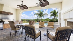 An outdoor patio with a grill, dining area, and pool view.