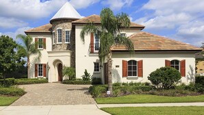 A two-story house with a stone facade, a conical roof, and a brick driveway.