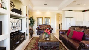 A living room with a television, leather sofas, a coffee table, and a large mirror. - Je47858 - Reunion Resort - 6 Bed 4 Baths Villa (Kissimmee)