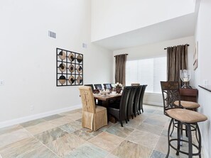 A dining area with a table set for four, surrounded by chairs, and a decorative wall piece above the table.