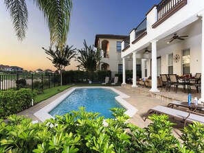A poolside area with a pool, outdoor furniture, and a two-story building with balconies.