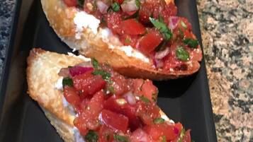 Four pieces of bruschetta on a black tray.