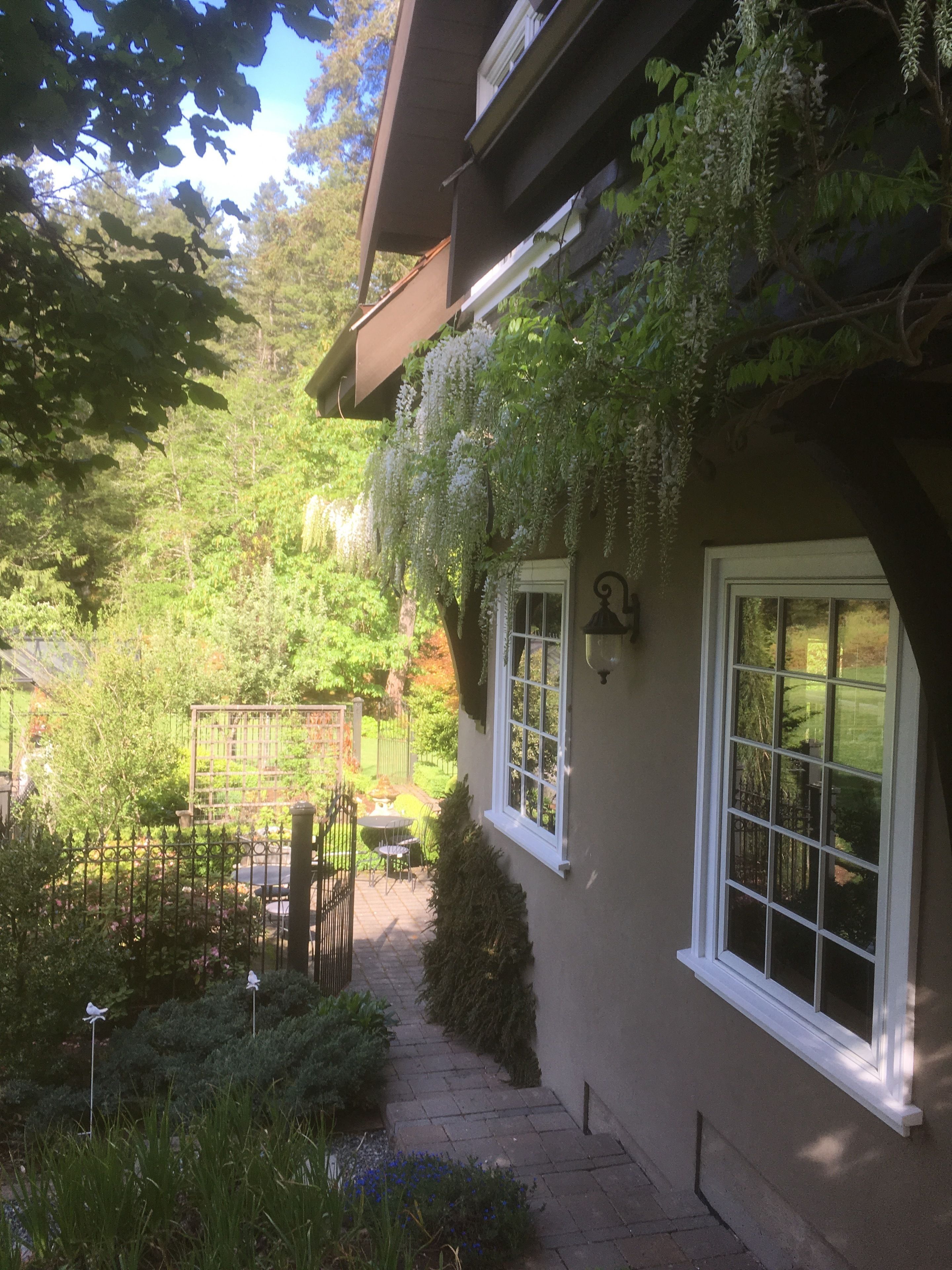 A house with a garden, a patio with a table and chairs, and a gate.