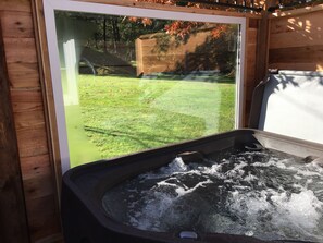 A hot tub with a view of a grassy yard and a wooden deck. - Amante Luxury B&B (Victoria)