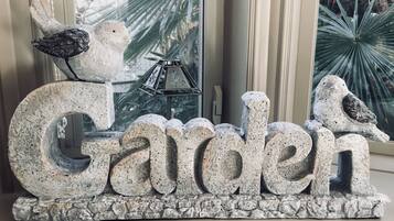 Un letrero decorativo con la palabra 'Garden' y dos pájaros posados encima.