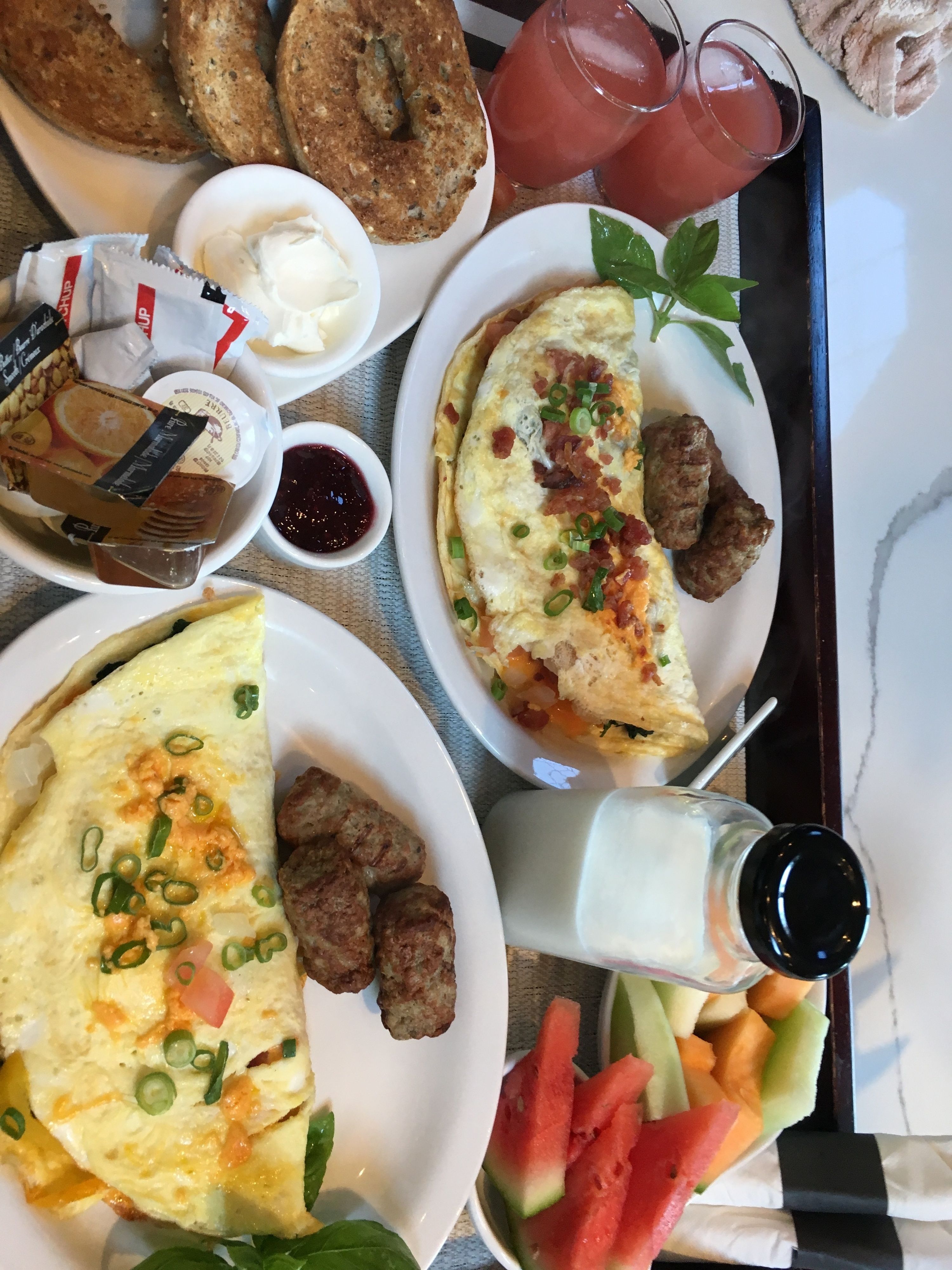 A breakfast tray with various dishes including eggs, sausage, toast, and fruit.