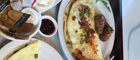 A breakfast tray with various dishes including eggs, sausage, toast, and fruit.