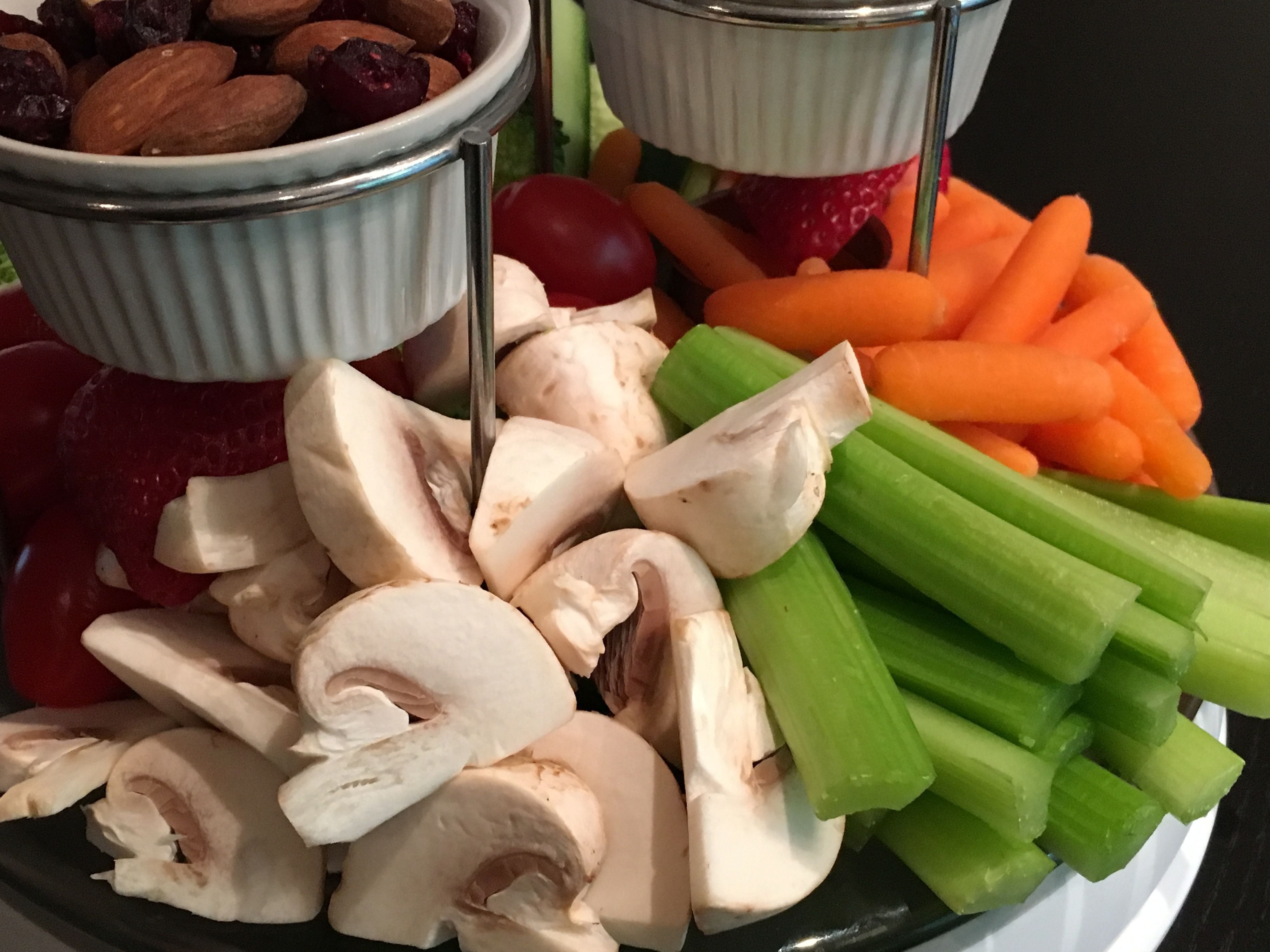 Un plato con champiñones en rodajas, apio, zanahorias, fresas y almendras.
