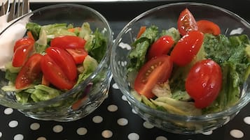 Dos ensaladeras de vidrio con tomates cherry sobre una bandeja negra con lunares blancos.