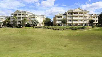 A large, multi-story hotel with a symmetrical facade, multiple balconies, and a well-maintained lawn in front.