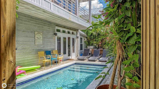 A pool area with lounge chairs, a grill, and a sign warning of a manatee.