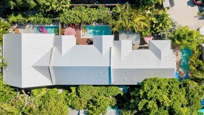 A modern hotel with a unique roof design, a swimming pool, and lush greenery.