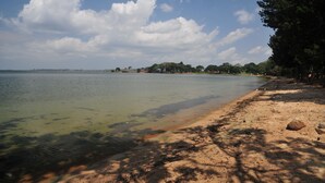 A beach with clear water, a sandy shore, and trees in the background. - Victoria Lake View Guest House & Safaris (Entebbe)