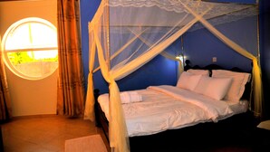 A bed with a canopy, a round window, and curtains. - Victoria Lake View Guest House & Safaris (Entebbe)