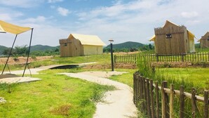 A rural setting with wooden structures, a dirt path, and a wooden fence. - Rai Ruen Rom Organic Farm (Thoeng)