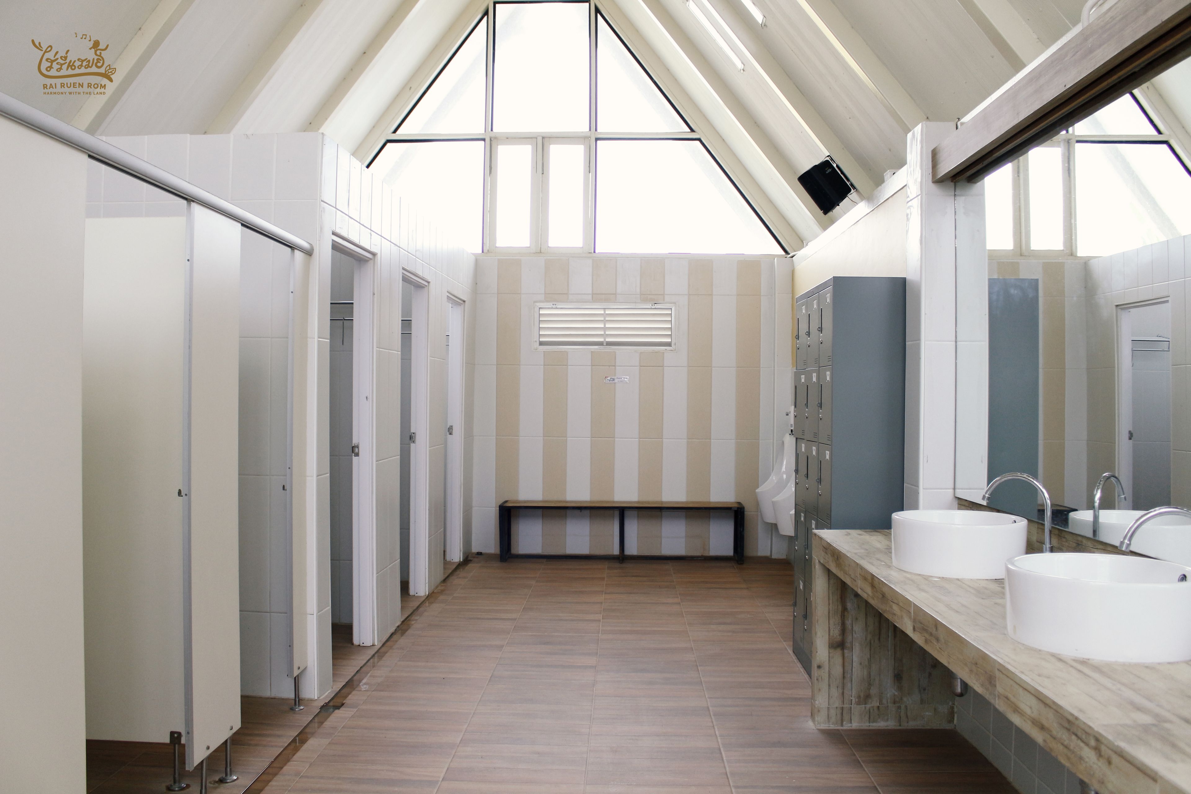 A modern bathroom with a sloped ceiling, multiple lockers, and two sinks.