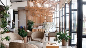 A modern interior with wicker furniture, large windows, and indoor plants. - Rai Ruen Rom Organic Farm (Thoeng)