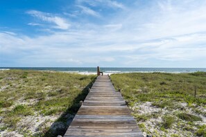 A wooden boardwalk leading to a bench overlooking a beach.