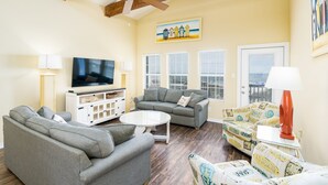 A living room with a sofa, armchairs, a coffee table, a TV, and a ceiling fan.