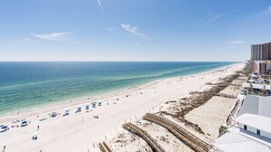 A beach with a wooden boardwalk, beach umbrellas, and a clear view of the ocean.