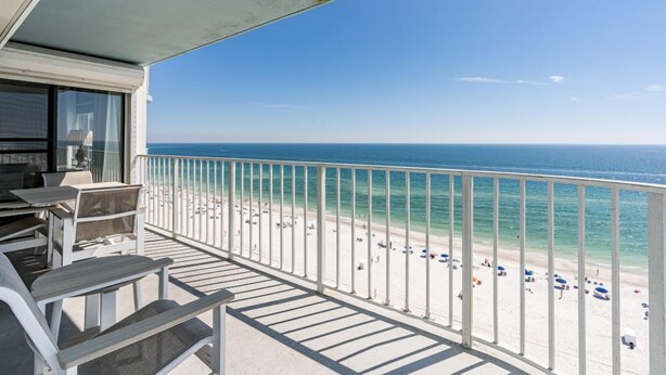 A balcony with a view of a beach and the ocean.