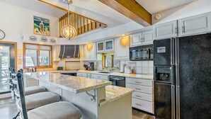 A modern kitchen with a central island, stainless steel appliances, and a dining area with bar stools. - Sunrise Beach Waterfront Estate Great for Families (Sunrise Beach)
