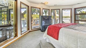 A bedroom with a large bed, a television, and a balcony with a view of the outdoors. - Sunrise Beach Waterfront Estate Great for Families (Sunrise Beach)