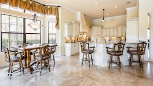 A spacious kitchen with a large island, white cabinetry, and a dining area with ornate chairs. - Je50286 - Reunion Resort - 5 Bed 5 Baths Villa (Kissimmee)