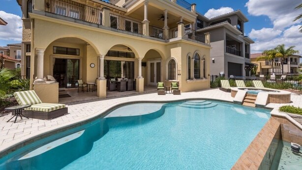 A large, two-story house with a swimming pool, outdoor seating, and a balcony. - Je50286 - Reunion Resort - 5 Bed 5 Baths Villa (Kissimmee)