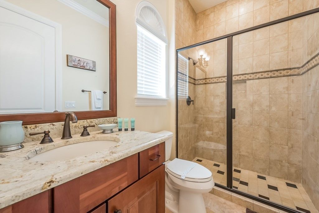 A bathroom with a double sink, vanity, and a glass-enclosed shower.