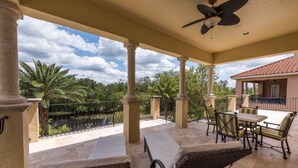A covered outdoor area with lounge chairs, a table, and a ceiling fan. - Je50286 - Reunion Resort - 5 Bed 5 Baths Villa (Kissimmee)