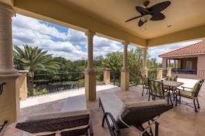 Relax in a serene outdoor space with a patio, wicker chairs, and a table, surrounded by lush greenery and a tranquil view.