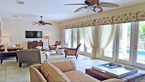 A spacious living room with a ceiling fan, comfortable seating, a flat-screen TV, and large windows with curtains. - Je37919 - Reunion Resort - 4 Bed 4 Baths Villa (Kissimmee)