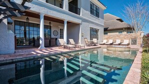 Ein zweistöckiges Haus mit Swimmingpool, Außenbereich mit Sitzgelegenheiten und einer überdachten Terrasse.