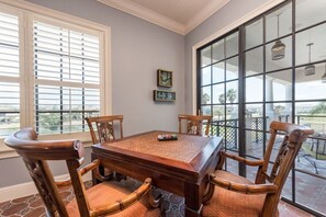 Un coin repas avec une table et des chaises en bois, une fenêtre avec des stores et une vue sur l’extérieur.