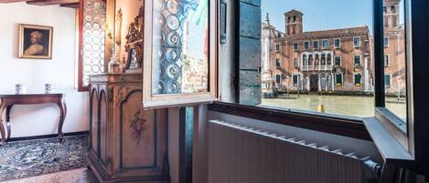 A room with a view of historic buildings, a radiator, a wooden cabinet, and a patterned window.