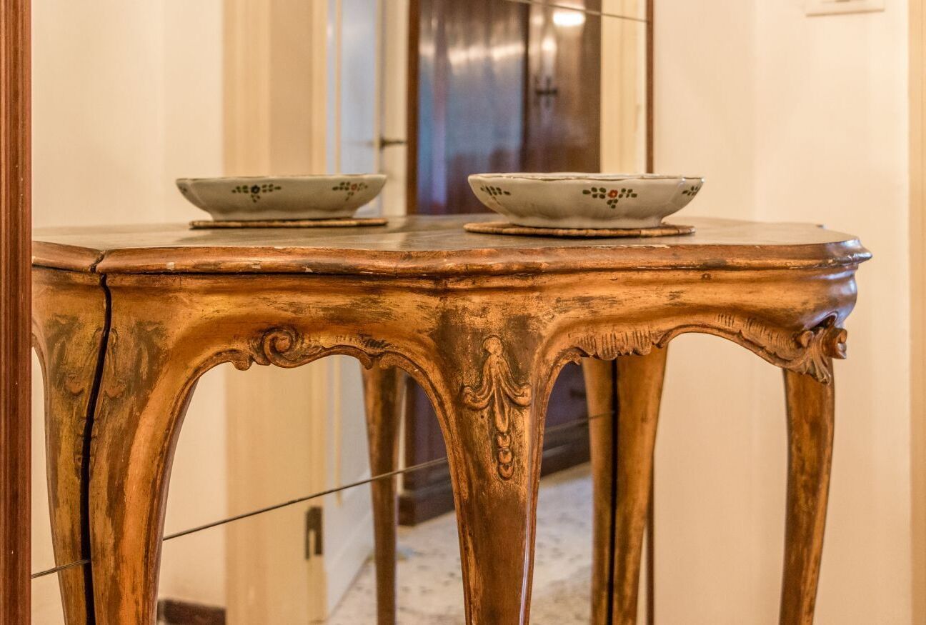 A wooden table with ornate carvings and two bowls on top.
