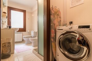 Une buanderie équipée d’un lave-linge à chargement frontal, de toilettes et d’un évier.