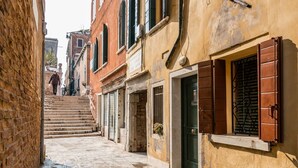 A narrow street with stone steps leading to a building with a green door and a window with shutters. - VIVALDI APARTMENT ON TWO LEVELS WITH ATTIC (Venezia)
