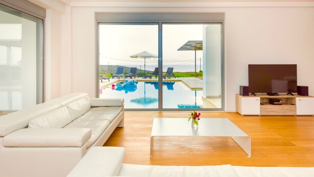 A modern living room with a large sliding glass door leading to a pool area.