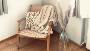 A corner room with a wooden chair, a patterned cushion, a woven wall hanging, and a vase with pampas grass. - Landhotel Sonnenhof (Siebeldingen)
